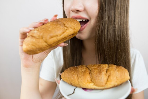 Photo young beautiful girl eating a croissant closeup crop photo female mouth eating croissant