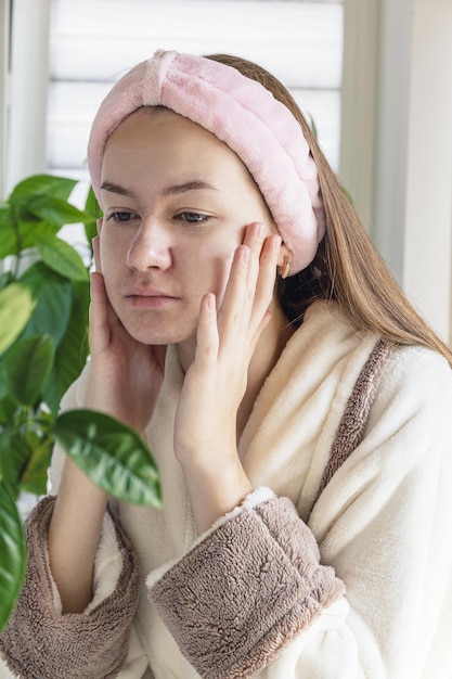 Young beautiful girl gets eyebrow correction, plucking hair with tweezers home. Self care.