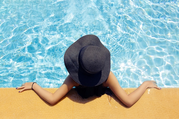 Young beautiful girl in a hat by the pool, top view