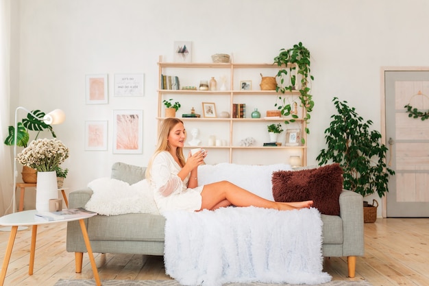 Young beautiful girl having a cup of coffee on a couch.