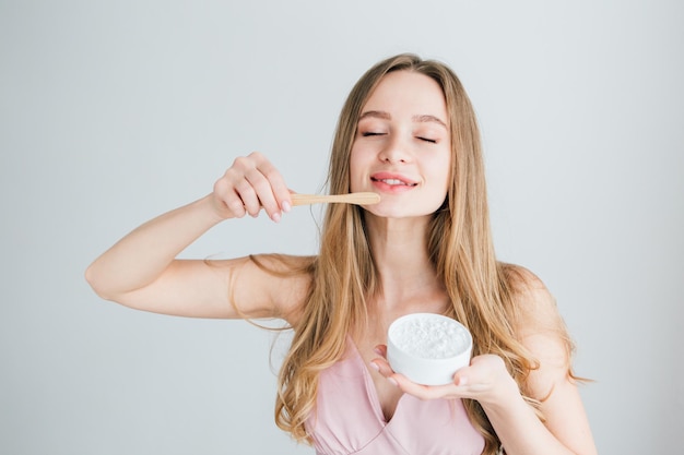 Young beautiful girl holding a useful bamboo toothbrush and a jar of tooth powder. the concept of a healthy lifestyle, environmental friendliness and zero waste. toning.