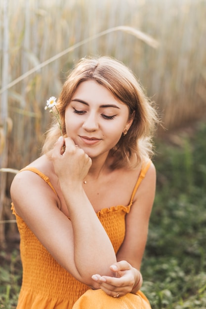 若い美しい少女はカモミールの花を持っています