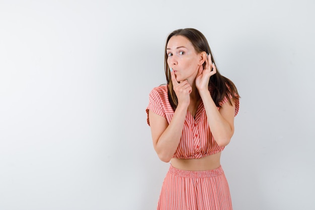 The young beautiful girl is listening by placing her hand  behind her ear on  white background.