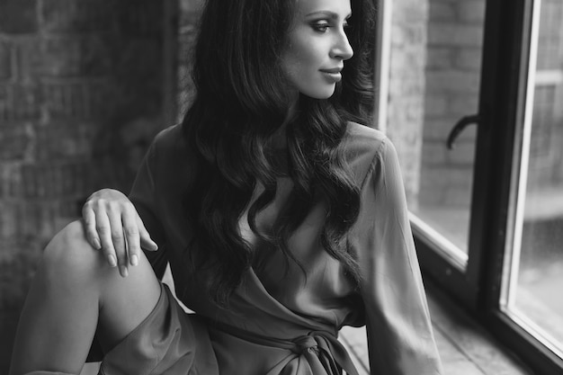 Young beautiful girl is sitting by the window. romantic image in a dress.