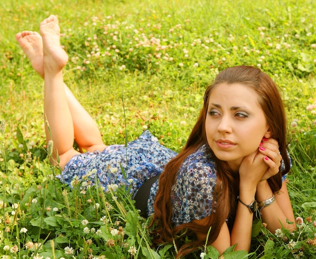 Young beautiful girl lays on a grass