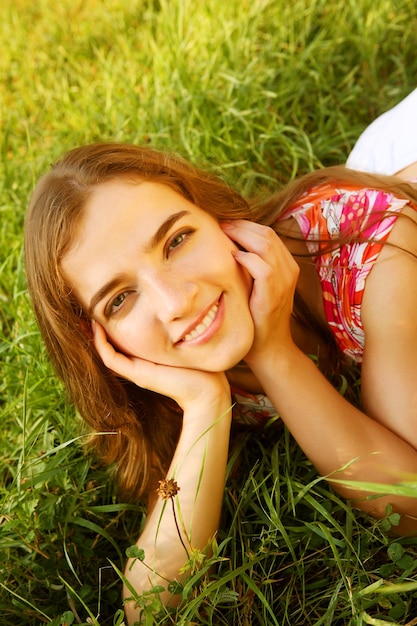 Young beautiful girl lays on a grass