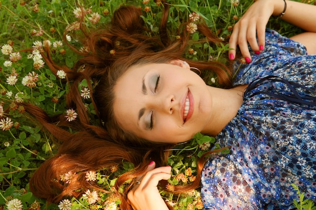 Young beautiful girl lays on a grass