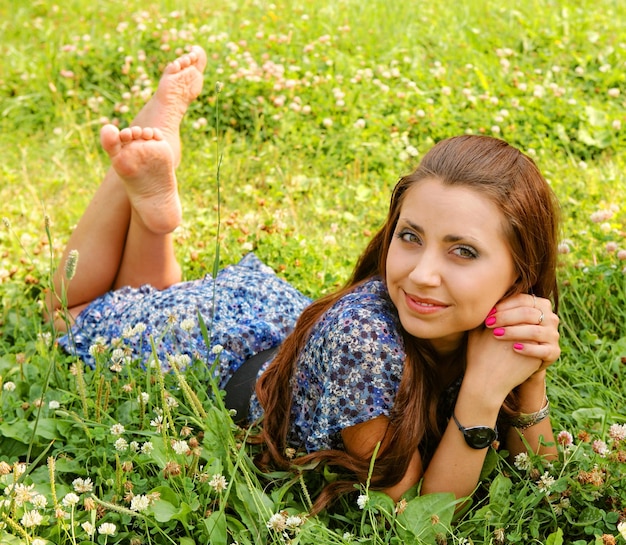 Young beautiful girl lays on a grass