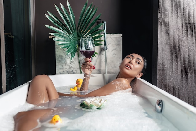 Young beautiful girl looking to the side, posing while lying in a foam bath