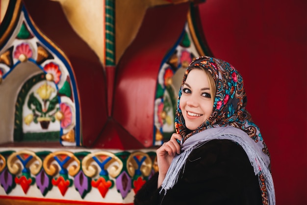 A young beautiful girl in a mink coat and a Russian folk scarf walks around moscow