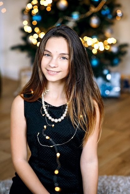 Молодая красивая девушка возле новогодней елки радостно улыбается