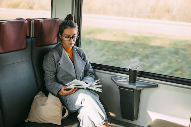 写真 電車の中で旅行中に本を読んでいる電車の中で美しい少女。