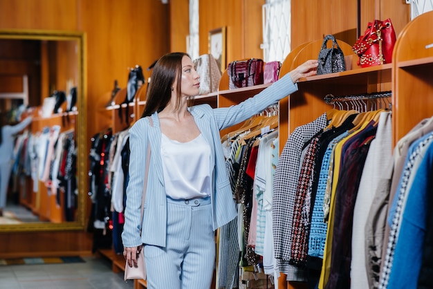 Una giovane bella ragazza prende i vestiti e va a fare shopping nel negozio.