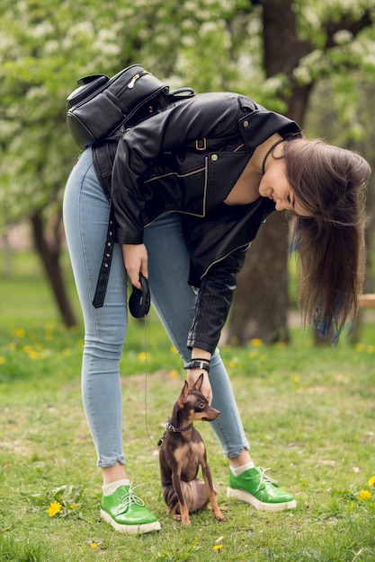 Young beautiful girl playing with dog outdoors