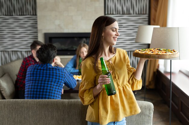 写真 若い美しい女の子がカフェでビールとピザでポーズをとる