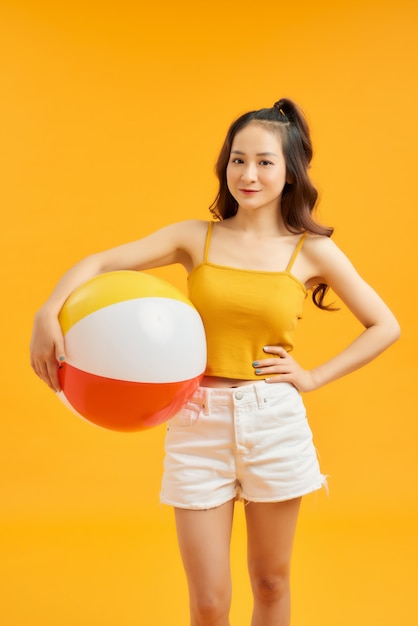 Young beautiful girl posing isolated over orange wall