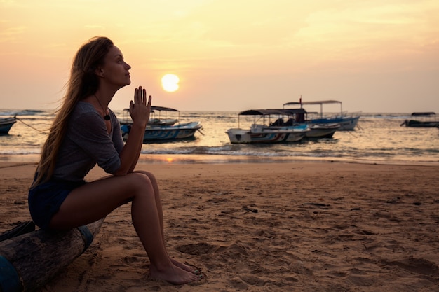 Young beautiful girl praying by the ocean