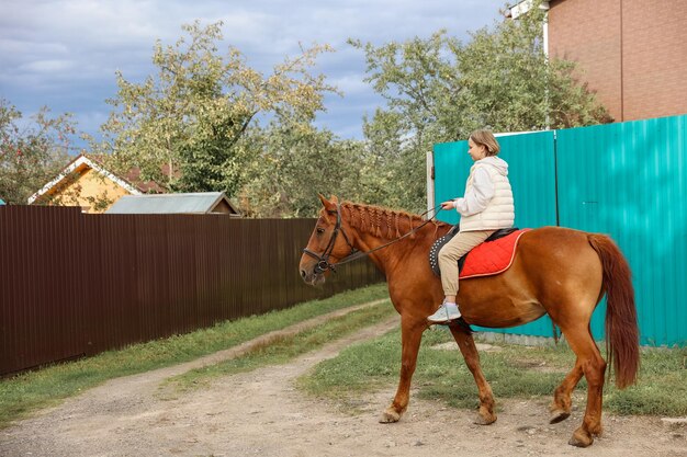 Фото Молодая красивая девушка осенью едет на лошади по проселочным дорогам