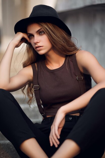 Young beautiful girl in a short elegant top and black hat