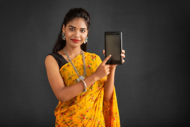 Young beautiful girl showing a blank screen of a smartphone or mobile or tablet phone