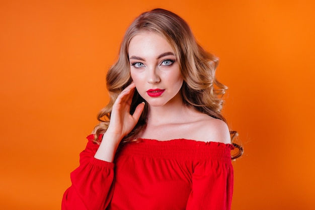 A young beautiful girl shows emotions and smiles in the Studio on an orange background. Girls for advertising.