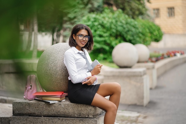 Young beautiful girl sitting near the university Portrait of a student Back to school concept