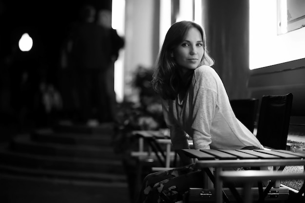 Young beautiful girl sitting in a street cafe at night