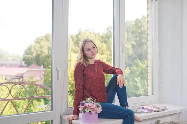 Young beautiful girl sitting on the windowsill 9102