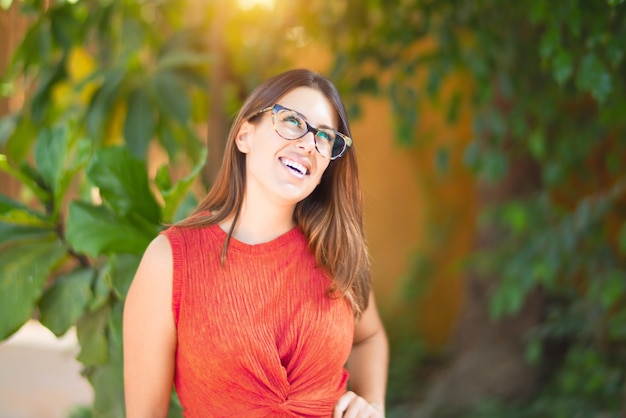 Young beautiful girl smiling happy and confident walking at the town park standing with a smile on face