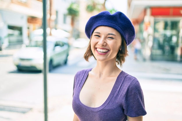 도시의 거리를 걷는 프랑스 스타일로 행복하게 웃고 있는 아름다운 소녀