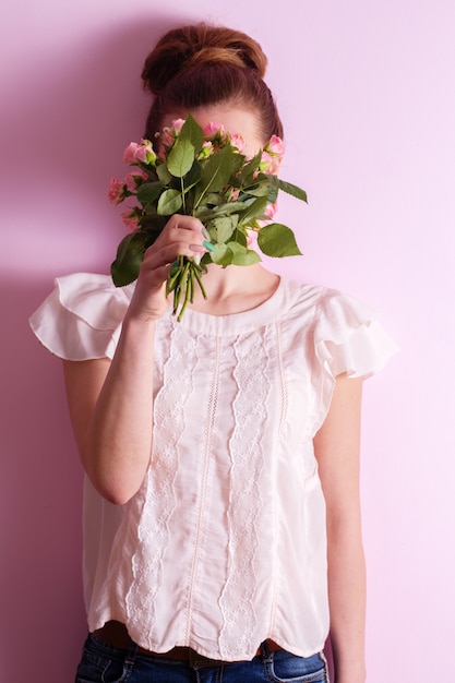 Young beautiful girl sniffing a bouquet of pink roses on valentine's day