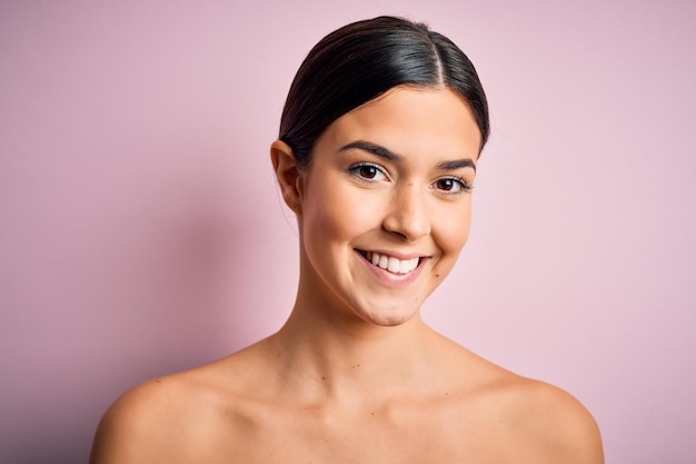 Young beautiful girl standing over isolated pink background with a happy face standing and smiling with a confident smile showing teeth