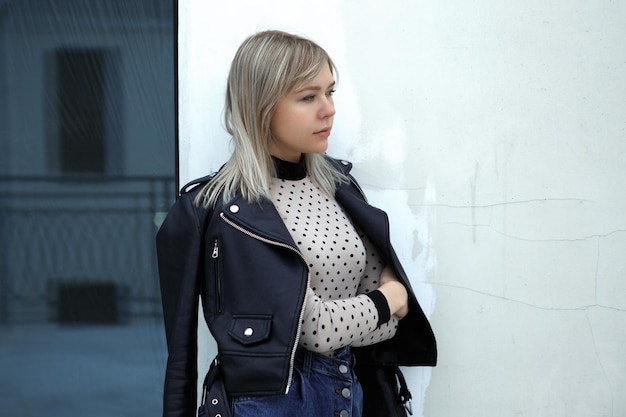 Young beautiful girl standing near the wall in the city.