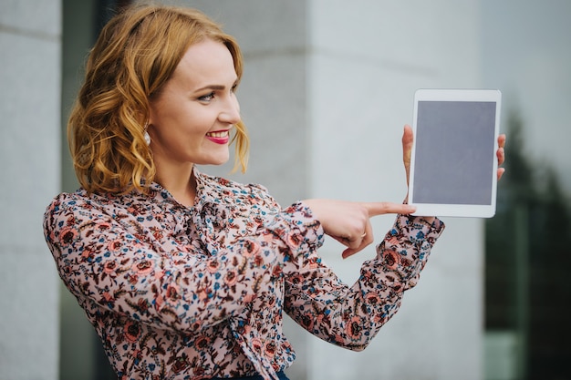 Young beautiful girl on the street with a tablet