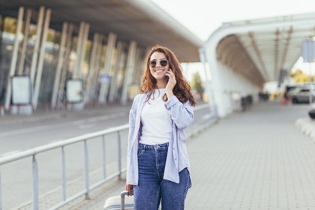 A young beautiful girl student leaves the airport in a new city and waits for a taxi