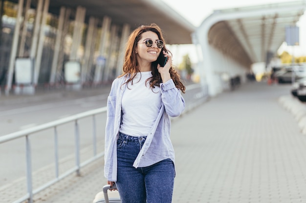 A young beautiful girl student leaves the airport in a new city and waits for a taxi