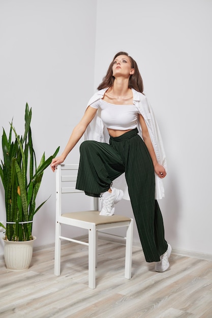 Young beautiful girl in stylish clothes stands on a chair