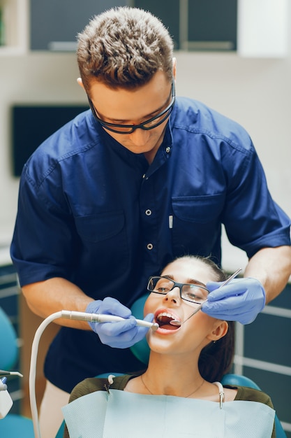 Photo a young and beautiful girl treats her teeth with a dentist