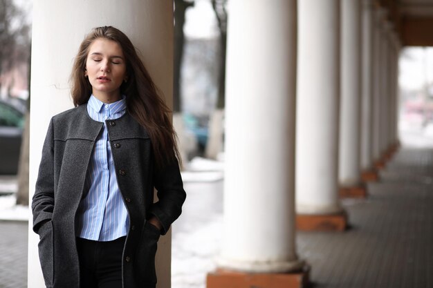 Photo young beautiful girl on a walk near building with a column