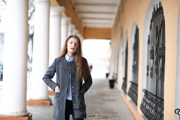 Young beautiful girl on a walk near a building with a column