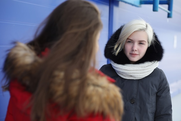 Young beautiful girl on a walk in winter at blue wall background