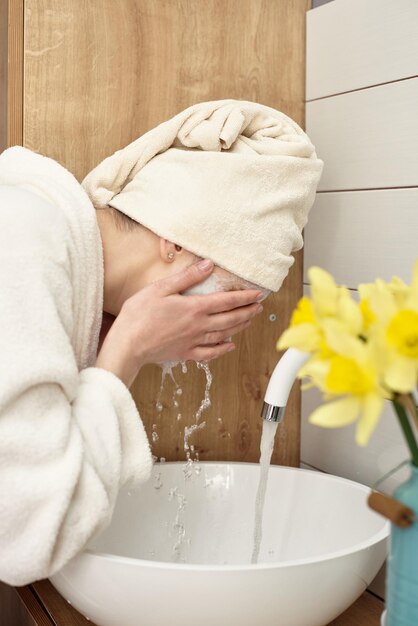 Young beautiful girl washes her face after applying the mask