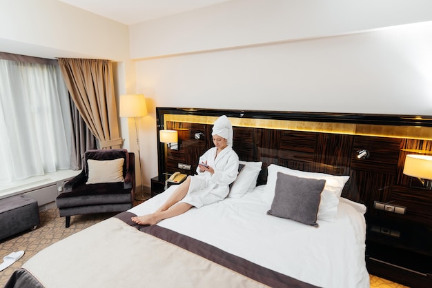 A young beautiful girl in a white coat is talking on the phone in her hotel room Rest and travel Hotel recreation and tourism