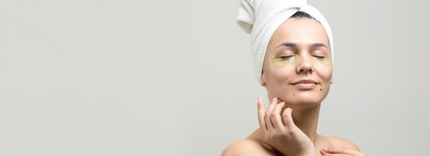 Young beautiful girl in a white towel on his head wears collagen gel patches under her eyes Mask under eyes treatment face