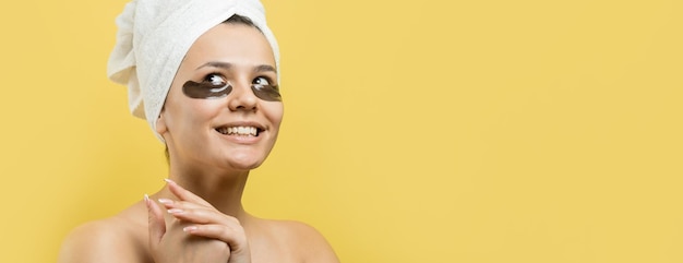 Young beautiful girl in a white towel on his head wears collagen gel patches under her eyes Mask under eyes treatment face