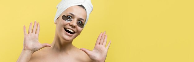Молодая красивая девушка в белом полотенце на голове носит пластыри с коллагеновым гелем под глазами Маска под глазами лечение лица