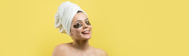 Young beautiful girl in a white towel on his head wears collagen gel patches under her eyes Mask under eyes treatment face