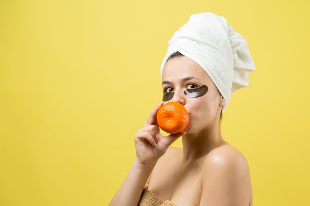 Young beautiful girl in a white towel on his head wears collagen gel patches under her eyes