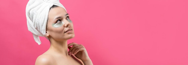 Young beautiful girl in a white towel on his head wears collagen gel patches under her eyes