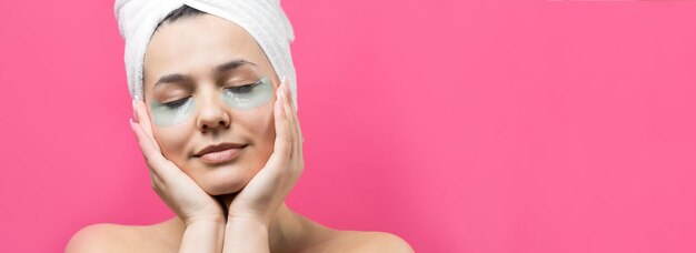 Young beautiful girl in a white towel on his head wears collagen gel patches under her eyes